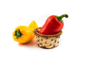 Red and yellow peppers in a basket, ingredient for a dish, on a white isolated background