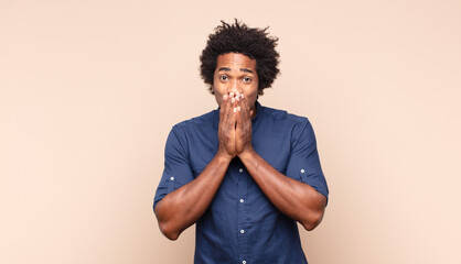 young black afro man looking happy and excited, shocked with an unexpected surprise with both hands...