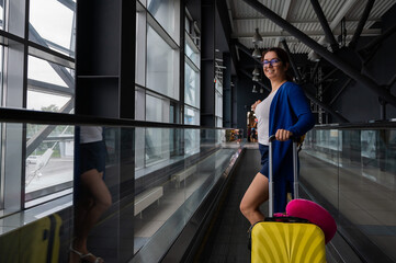 Caucasian woman on a horizontal escalator with a suitcase at the airport. A girl with pink luggage rides on a moving sidewalk