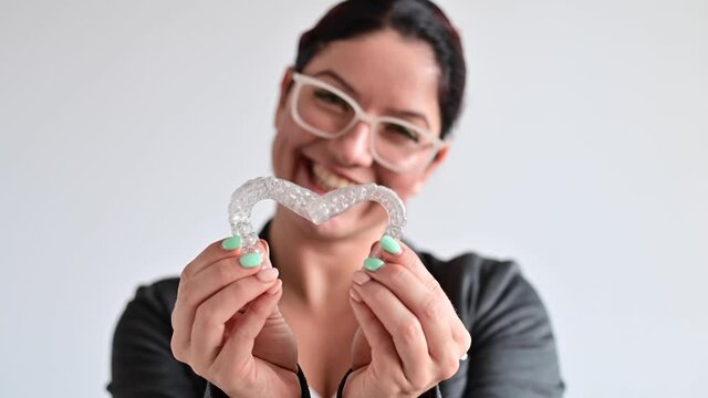 Caucasian woman holding two transparent heart-shaped aligners
