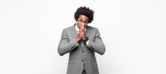 black afro businessmanfeeling worried, hopeful and religious, praying faithfully with palms...