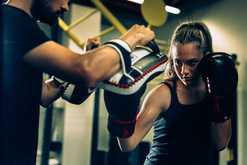 woman boxing with her trainer in gym