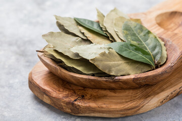 Bay leaf or laurel (laurus nobilis), sliced garlic & garlic clove on wooden background