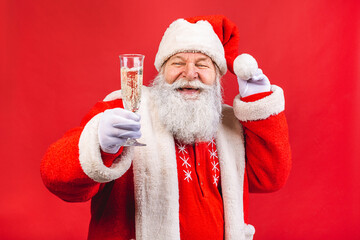 Santa Claus standing isolated on red background. Christmas and new year concept. Holding glass of champagne.