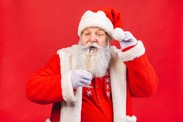 Santa Claus standing isolated on red background. Christmas and new year concept. Holding glass of champagne.