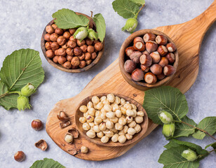 Top view of hazelnuts with peeled hazelnut and leaf  in brown bowl on concrete background.