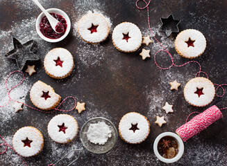 Traditional Christmas Linzer cookies with raspberry jam on dark background.