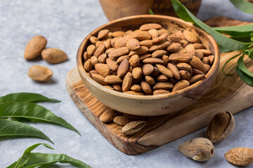 Peeled whole almonds  in bowl with leaf