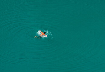 A man is swims in a forest lake Sea Eye with turquoise water. Rest on the lake.