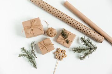 Christmas flat lay with fir pine branches,gift boxes,brown twine,gingerbread,and wrapping paper on the white background. Christmas preparation, gift wrapping concept