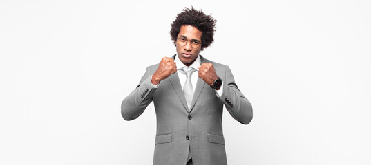 black afro businessmanlooking confident, angry, strong and aggressive, with fists ready to fight in...