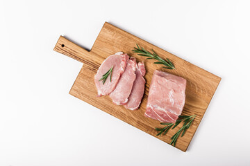 Raw pork sliced meat with rosemary on the wooden board. Flat lay on the white background.