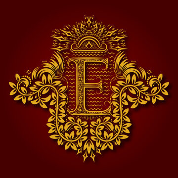 Letter E heraldic monogram in coats of arms form. Vintage golden logo with shadow on maroon background. Letter E is surrounded by floral elements of design.
