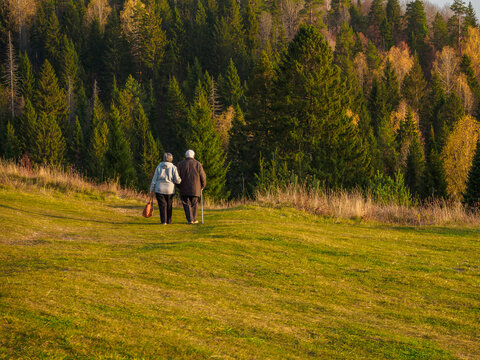 An elderly couple walks in a Stone Hill nature park in autumn day.