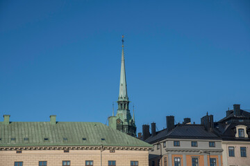 Fototapeta na wymiar German church tower and roofs at the old town Gamla Stan a morning in Stockholm