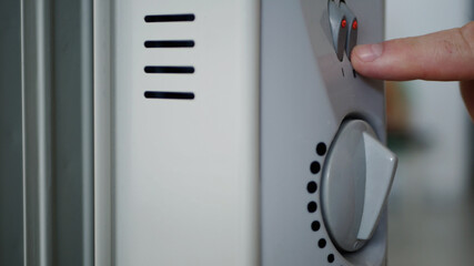 Image with a Hand Who Sets the Electric Heater Thermostat for Warming a Cold Room
