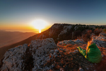 Girl watching the sunset on the top of the mountain