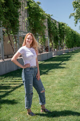 a Russian girl in jeans and a T-shirt with long white hair walks around a green park. Krasnodar Park