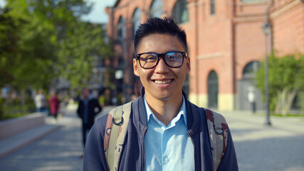 Portrait of young asian man in eyeglasses smiling and looking at camera.