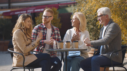 Senior couple with adult children outdoors in cafe disinfect hands 