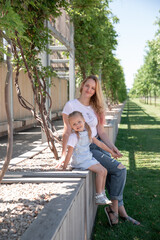 Fototapeta premium Beautiful mother and little daughter walking together in summer park