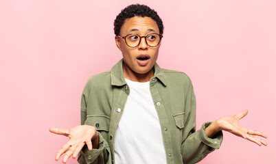 afro young black woman feeling extremely shocked and surprised, anxious and panicking, with a...