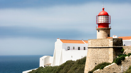Fototapeta na wymiar Red lighthouse overlooking the sea at Cabo San Vicente in Sagres, Portuguese Algarve