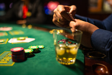 Person playing poker. Glass of cold drink. Casino chips.