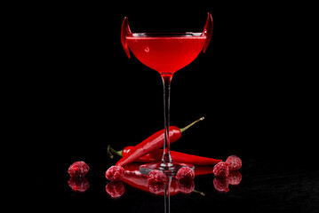 cocktail on a black background with red hot pepper and raspberries 