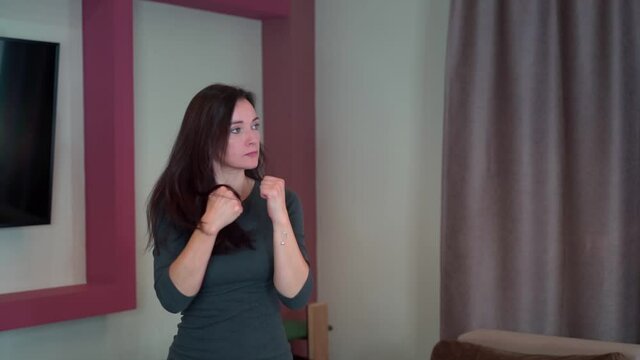 Young girl housewife in an aggressive state boxing at home in the air in slow motion.