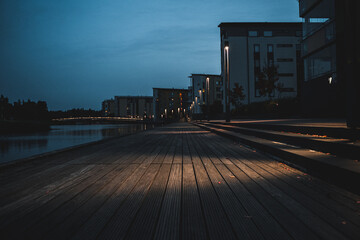 Buildings and small boardwalk next to water at night