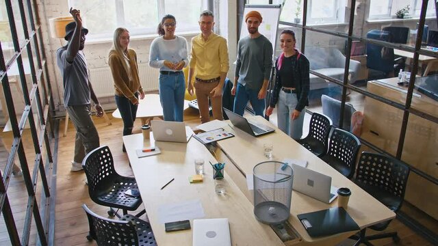 Millennial colleagues having fun in office, playing basketball game throwing paper in rubbish bin