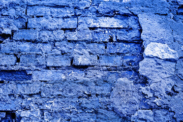 Old white brick wall with cracked plaster and black mold. Texture, background of old white brick wall with cracked plaster and black mold. The image is tinted in the color of the year-classic blue.