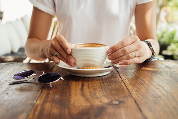 A cup of cappuccino in the hands of a girl. morning with coffee. coffee house