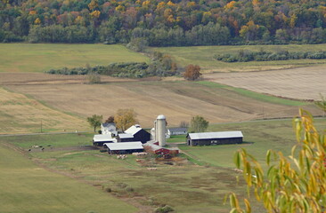 The aerial view of the farm surrounded by striking color of fall foliage near Wyalusing, Pennsylvania, U.S