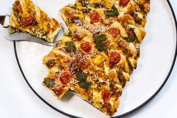 Homemade Christmas cake in the shape of a Christmas tree on a white background. Fresh pastries with tomatoes and cheese decorated with greenery.