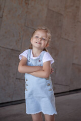 Cute kid girl 3-4 year old wearing trendy clothes posing in cityoutdoors. Looking at camera. Childhood. Autumn season.