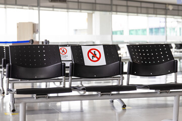 Empty waiting room at an airport during COVID-19 pandemic with social distancing signs on chairs