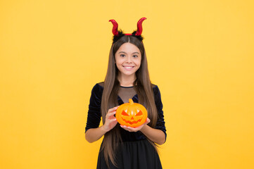 halloween kid in red imp horns playing trick o treat holding pumpkin jack o lantern, happy...
