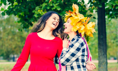 Portrait of happy mother and daughter in autumn forest. Young Mother and daughter walking in the autumn park. Autumn women brunettes.