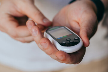 medicine, diabetes, glycemia, healthcare and people concept - loved one checking blood sugar with glucometer and test strip at home. Diabetes day, 14 November.