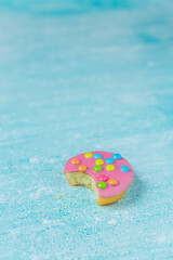 Pink glazed cookies on a blue background/surface. Dutch  cookies called Confettinis. It's a flat cake with pink fondant glazing and sprinkles.