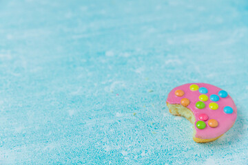 Pink glazed cookies on a blue background/surface. Dutch  cookies called Confettinis. It's a flat cake with pink fondant glazing and sprinkles.