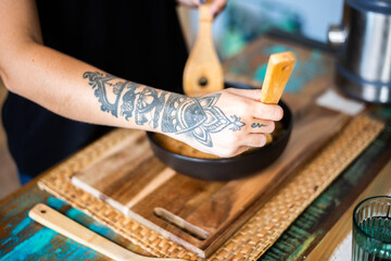Fototapeta na wymiar Mujer tatuada cocina comida oriental sobre plato negro.