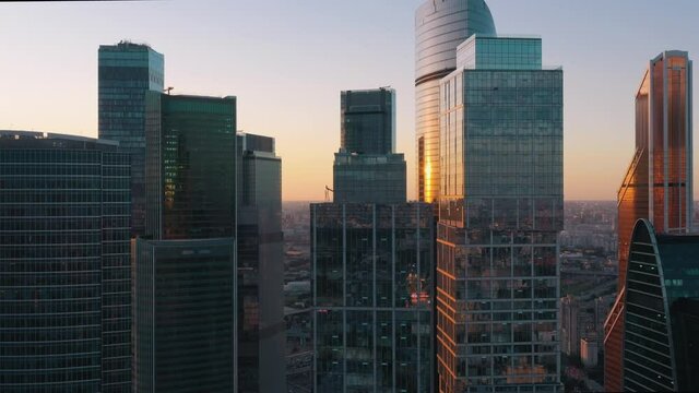 Moscow city glass skyscrapers drone zoom in moving to the buildings, sun reflection in the windows. Moscow International Business Center at the sunset, evening