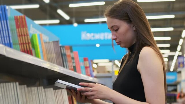 Young female is buying a book in a store