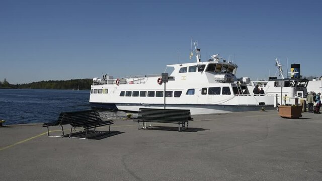 Passengers disembark the commuting boat Mysing in the harbor at the archipelago town Vaxholm in the archipelago of Stockholm a sunny summer day