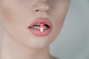 Pill between lips. Close up young woman with medicine pill in her sensual mouth