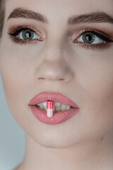 Pill between lips. Close up young woman with medicine pill in her sensual mouth