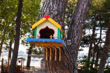 Handmade birdhouse hanging on the tree with chains in park